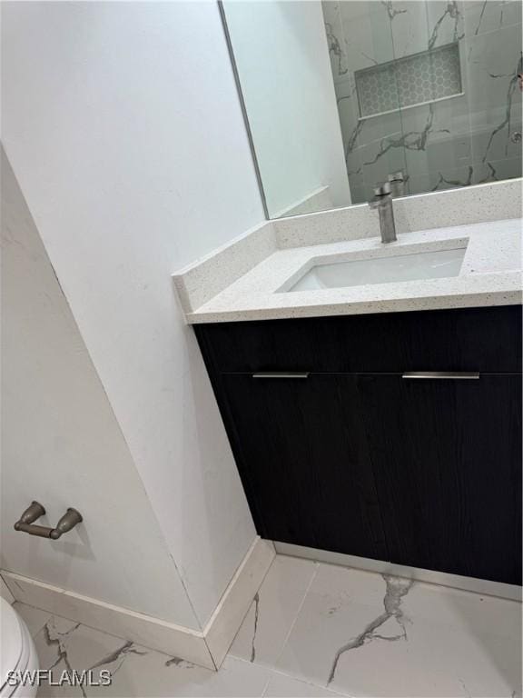 full bathroom featuring marble finish floor, a marble finish shower, toilet, vanity, and baseboards