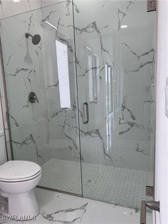 bathroom featuring toilet and a marble finish shower