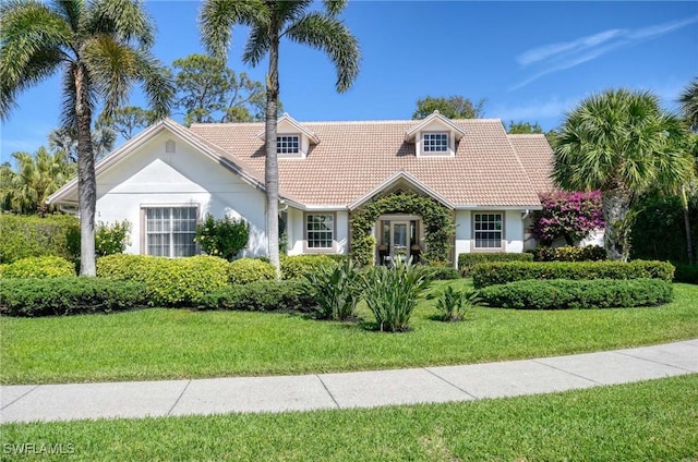 view of front of home featuring a tiled roof, a front lawn, and stucco siding