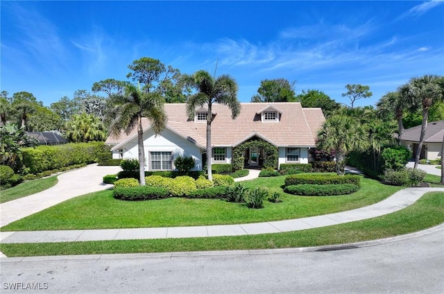 view of front facade featuring a tiled roof, a front lawn, and concrete driveway