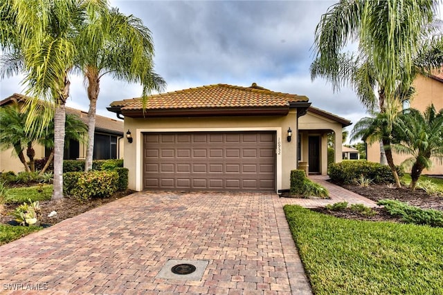 mediterranean / spanish house with decorative driveway, an attached garage, and stucco siding