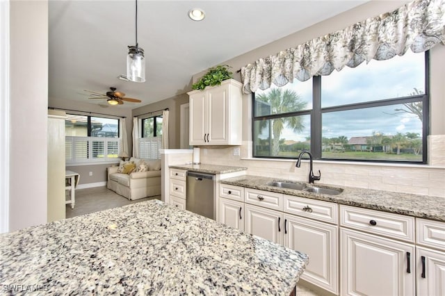 kitchen with a sink, white cabinetry, backsplash, light stone countertops, and dishwasher