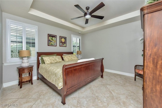 bedroom featuring light tile patterned floors, a raised ceiling, and baseboards