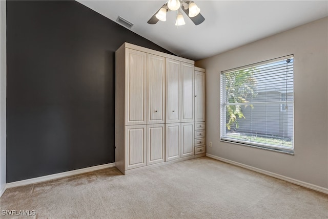 unfurnished bedroom featuring lofted ceiling, baseboards, visible vents, and light colored carpet