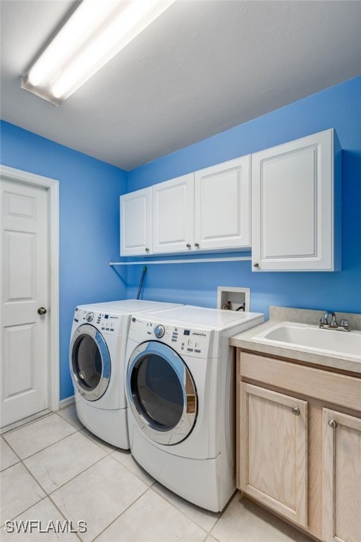 washroom featuring light tile patterned floors, washing machine and clothes dryer, a sink, and cabinet space