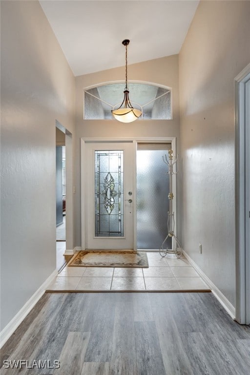 foyer featuring high vaulted ceiling, baseboards, and wood finished floors