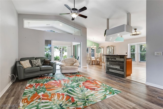 living room featuring lofted ceiling, baseboards, and light wood finished floors