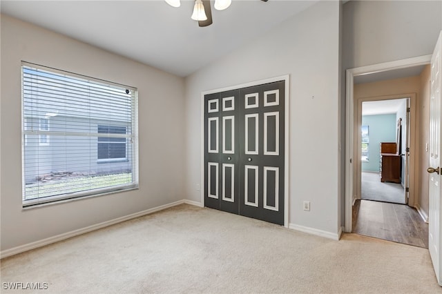 unfurnished bedroom with a closet, a ceiling fan, carpet flooring, vaulted ceiling, and baseboards