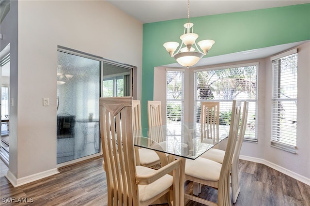 dining space featuring baseboards, a chandelier, and wood finished floors