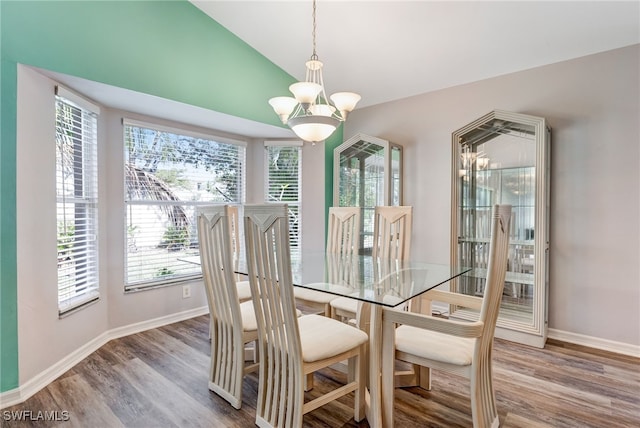 dining space with a notable chandelier, vaulted ceiling, a wealth of natural light, and wood finished floors