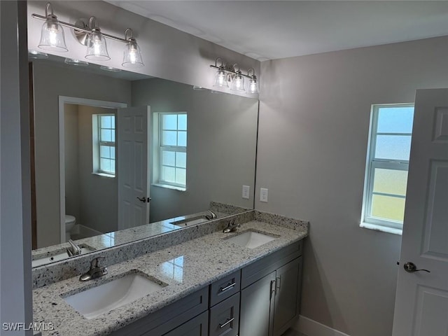 bathroom featuring double vanity, a sink, and toilet