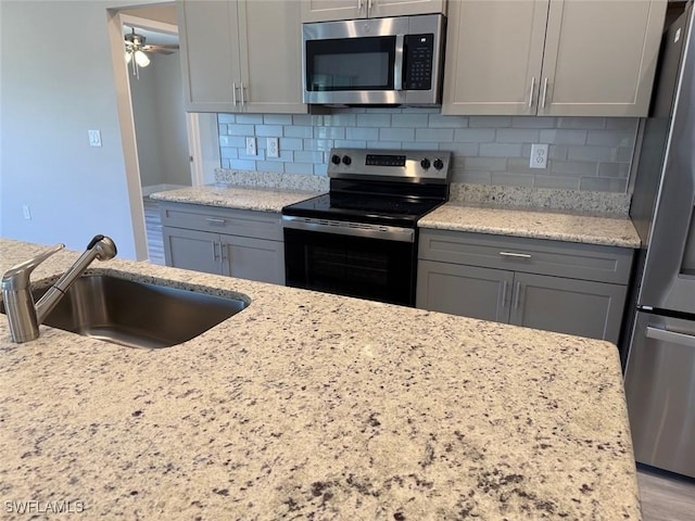 kitchen with appliances with stainless steel finishes, gray cabinets, and a sink