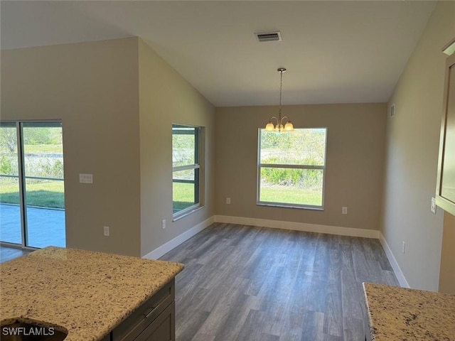 unfurnished dining area featuring dark wood-style flooring, visible vents, an inviting chandelier, vaulted ceiling, and baseboards