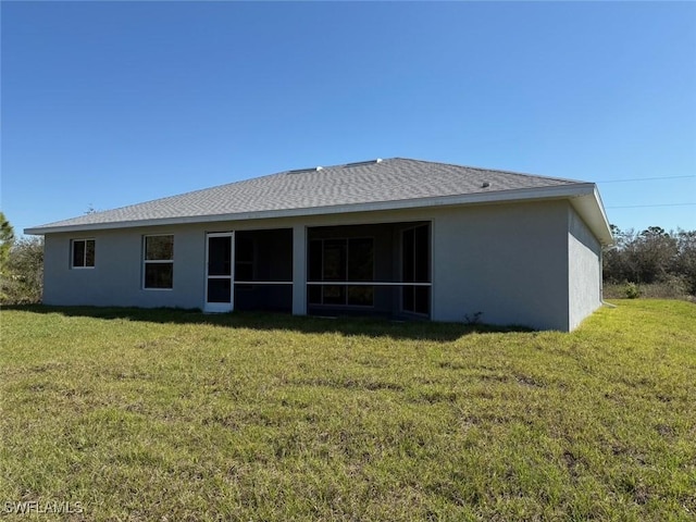 rear view of property with a yard, roof with shingles, a sunroom, and stucco siding