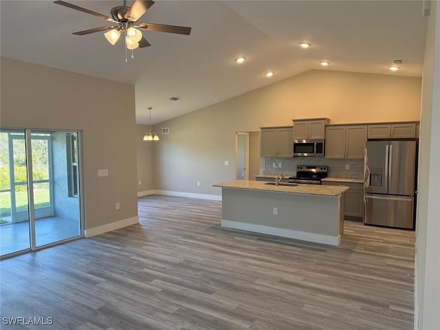 kitchen featuring an island with sink, appliances with stainless steel finishes, hanging light fixtures, gray cabinetry, and a sink