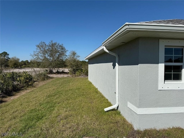 view of side of property with a lawn and stucco siding