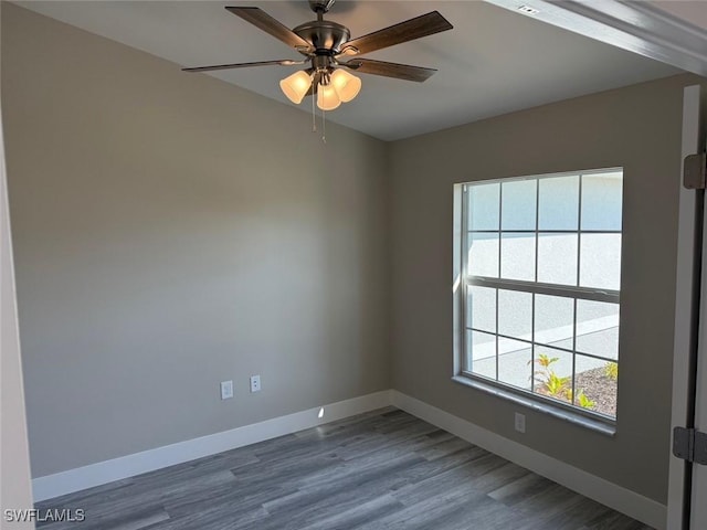 unfurnished room with baseboards, dark wood finished floors, and a ceiling fan