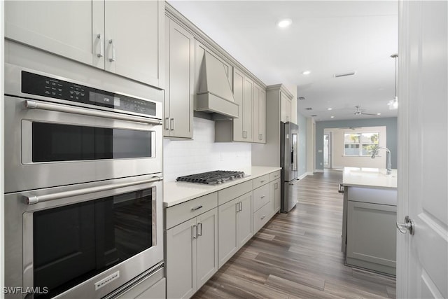 kitchen with stainless steel appliances, light countertops, gray cabinets, and custom range hood