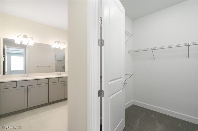 spacious closet featuring light tile patterned floors and a sink