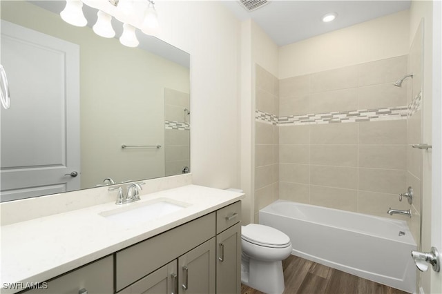 full bath featuring toilet, wood finished floors, visible vents, vanity, and shower / washtub combination