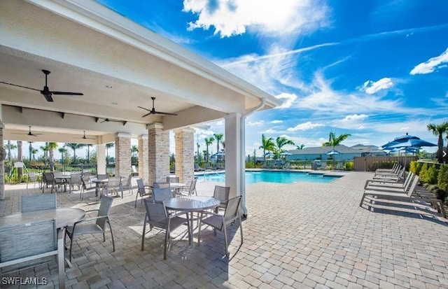 community pool with ceiling fan, a patio, outdoor dining space, and fence