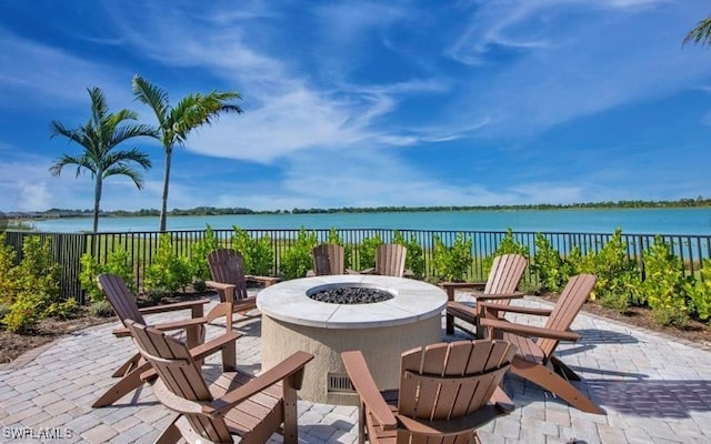 view of patio with a water view, fence, and a fire pit