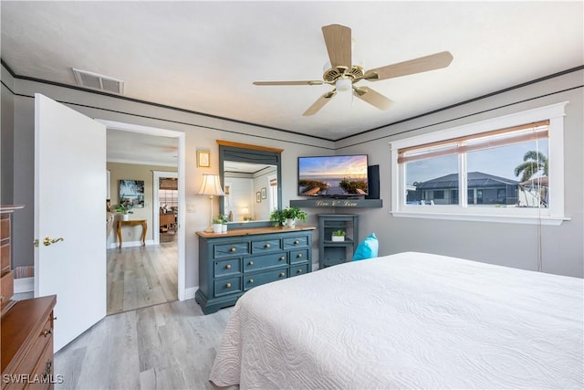 bedroom with a ceiling fan, light wood-style flooring, visible vents, and baseboards