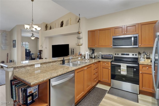 kitchen featuring stainless steel appliances, hanging light fixtures, a sink, and a peninsula