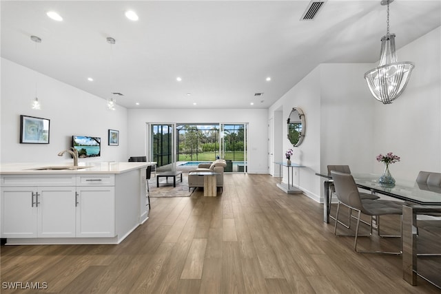 kitchen with recessed lighting, wood finished floors, a sink, white cabinets, and open floor plan