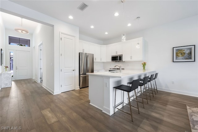 kitchen with stainless steel appliances, a breakfast bar, a peninsula, a sink, and light countertops