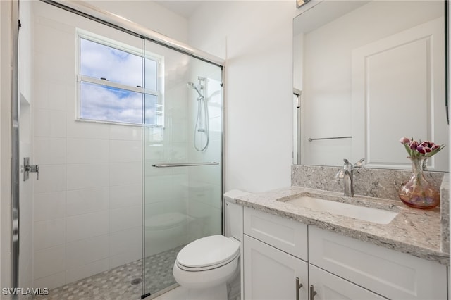 bathroom with vanity, a shower stall, and toilet