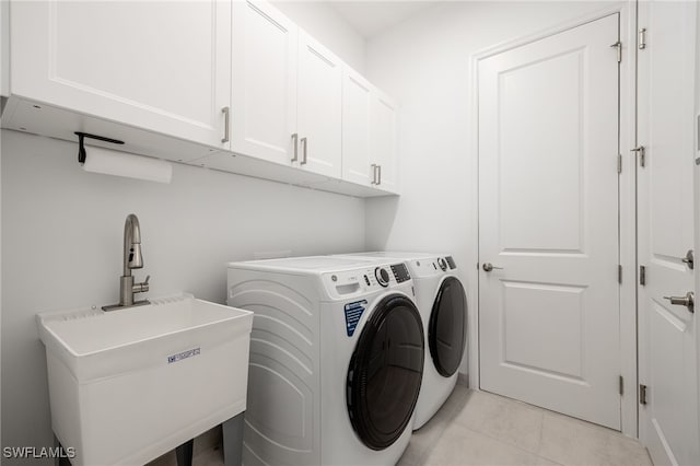 washroom with washing machine and dryer, cabinet space, a sink, and light tile patterned floors