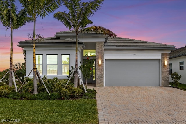 view of front of property featuring a garage, decorative driveway, and stucco siding