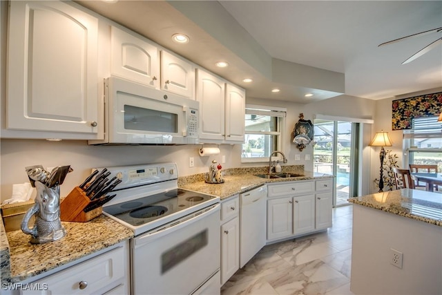 kitchen featuring light stone counters, white appliances, white cabinetry, and a sink