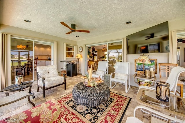 living area with ceiling fan and a textured ceiling