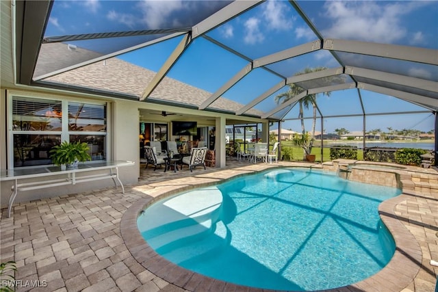 view of pool featuring a pool with connected hot tub, outdoor dining space, a patio area, ceiling fan, and a lanai