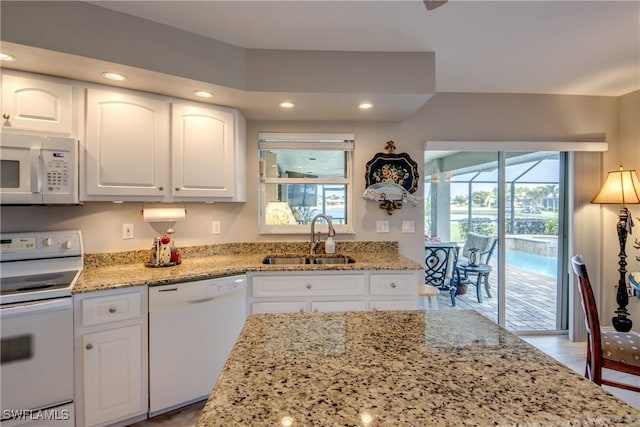 kitchen featuring white appliances, a sink, light stone countertops, and white cabinets