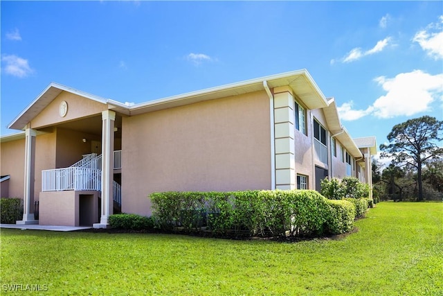 view of side of home featuring stucco siding and a yard