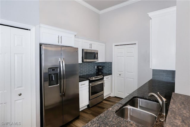 kitchen featuring a sink, ornamental molding, appliances with stainless steel finishes, decorative backsplash, and dark stone countertops