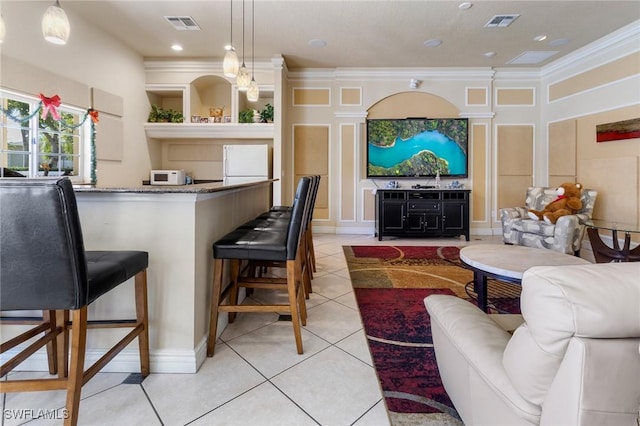 kitchen with light tile patterned floors, white appliances, visible vents, a kitchen breakfast bar, and crown molding