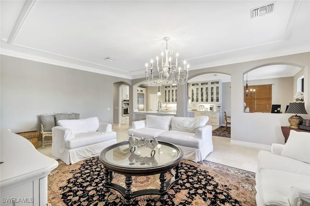 living area featuring visible vents, baseboards, ornamental molding, arched walkways, and a notable chandelier