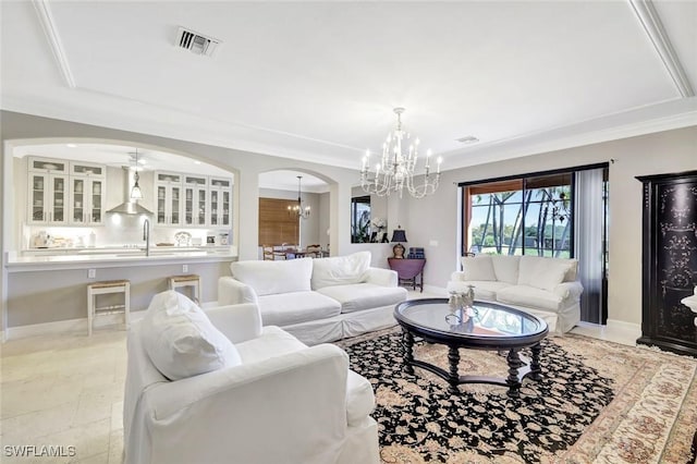 living room featuring visible vents, baseboards, arched walkways, ornamental molding, and ceiling fan with notable chandelier