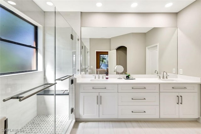 bathroom featuring double vanity, a stall shower, and a sink