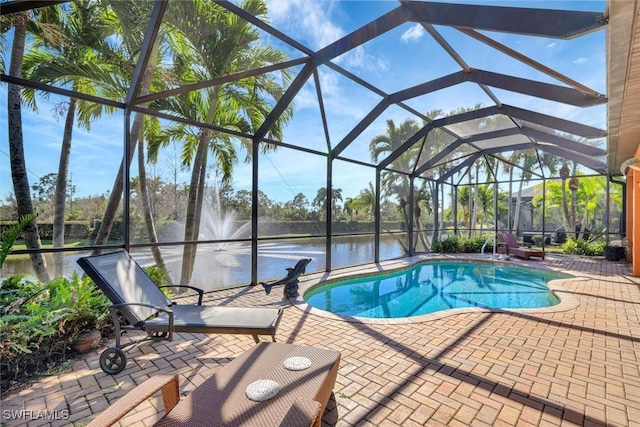 pool featuring glass enclosure, a water view, and a patio area