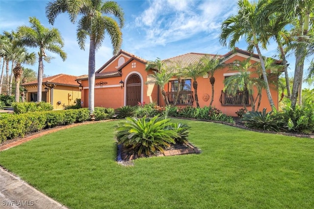 mediterranean / spanish-style house with a tile roof, a front lawn, a garage, and stucco siding