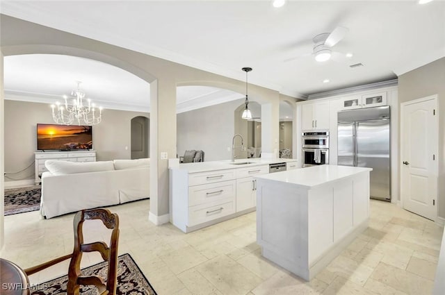 kitchen featuring light countertops, ceiling fan with notable chandelier, appliances with stainless steel finishes, arched walkways, and a sink