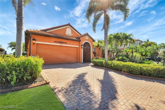 mediterranean / spanish-style house with stucco siding, decorative driveway, a garage, and a tiled roof