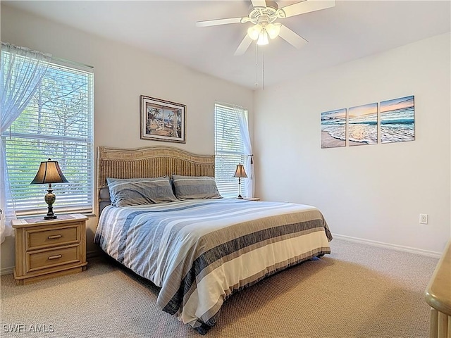 bedroom with a ceiling fan, light colored carpet, and baseboards
