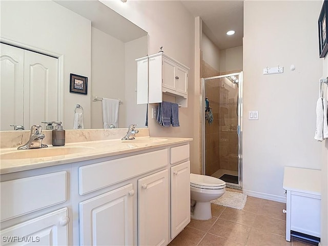 bathroom featuring tile patterned flooring, a stall shower, double vanity, and a sink