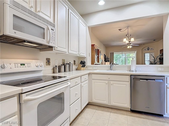 kitchen with a sink, white appliances, and white cabinetry